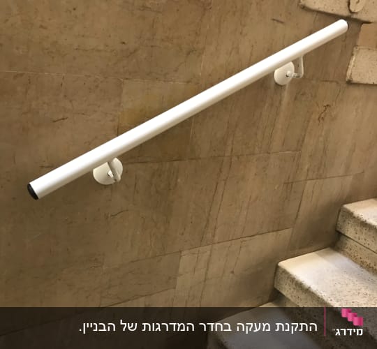 מעקה לבן מותקן על קיר מדרגות פנימי